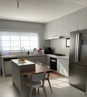 Cozinha planejada branca com ilha central e mesa integrada, executada em Campinas