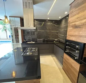 Cozinha planejada em tons escuros com coifa de inox e bancada de granito preto, projeto executado em Campinas