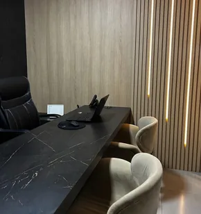 Home office planejado com painel ripado, iluminação LED e bancada em granito preto, executado em Campinas