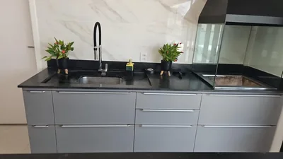 Área gourmet planejada em cinza com ilha e bancada de granito preto, executada em Campinas