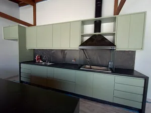 Área gourmet planejada em verde com coifa e bancada de granito preto, executada em Campinas