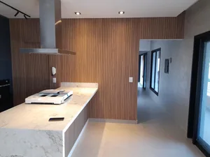 Cozinha planejada com ilha em madeira e bancada de mármore, integrada ao living, executada em Campinas