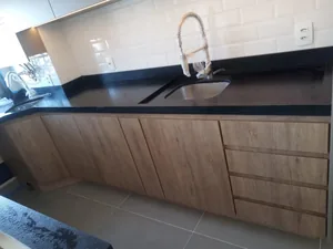 Cozinha planejada com armários em madeira e bancada de granito preto, executada em Campinas