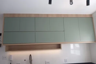Cozinha planejada em verde com bancada de granito preto e armários superiores, executada em Campinas